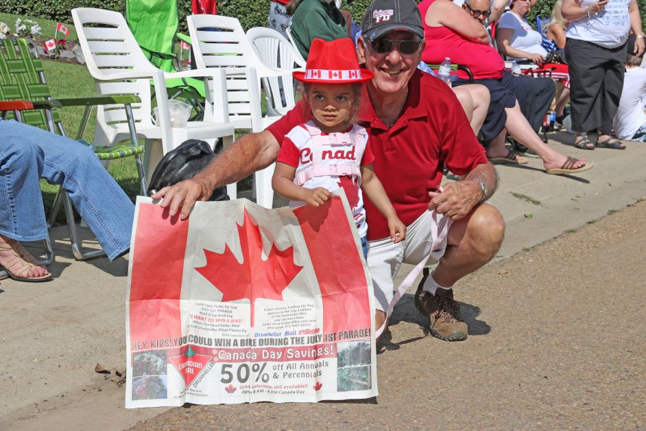 Canada Day parade goers show off their Drumheller Mail Canada Day flag in the hopes of winning a new bike. (mailphoto by Pat Kolafa)